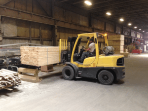 An employee maneuvers lumber in position to be trimmed to size. 